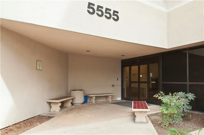 Covered main entrance of 5555 Reservoir Drive with stone benches beside the glass doors
